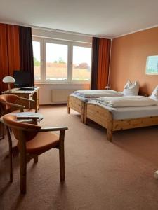 a hotel room with two beds and a chair and a desk at Neustädter Hof Hotel Garni in Neustadt am Rübenberge