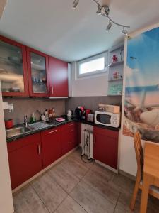 una cocina con armarios rojos y fregadero en chez moumie jacuzzi privatif, en Bevaix