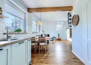 フミエルノにあるApartament Lazurowyの白いキャビネットとテーブルのあるキッチンとダイニングルーム +7枚の写真