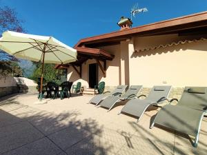 una fila de sillas y una sombrilla en un patio en IseoLakeRental - Chalet Giulia, en Sovere