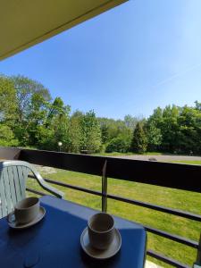 einen blauen Tisch mit zwei Tassen auf dem Balkon in der Unterkunft Your Stay in Kelmis - La Calamine- Cosy apartment in the Ardennes -Three-country point in Kelmis