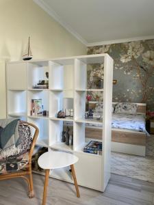 a white bookcase in a room with a bed and a chair at Flower House in the City Center! in Pristina