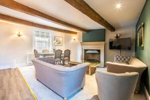 a living room with couches and a table and a tv at The Aubrey - a gorgeous converted 17th Century Grade II listed bolthole in Bakewell in Bakewell