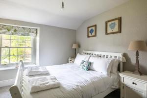 a bedroom with a white bed and a window at The Aubrey - a gorgeous converted 17th Century Grade II listed bolthole in Bakewell in Bakewell
