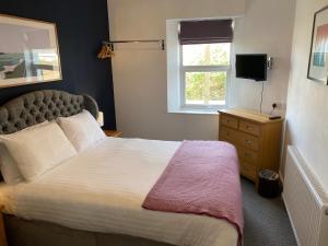um quarto com uma cama grande e uma janela em The Grosvenor Guest House em Bude
