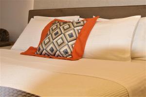a bed with orange and white pillows on it at Aiolos Apartments Ermou 64 2nd Floor suites in Athens