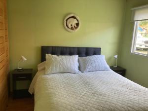 1 dormitorio con 1 cama con sábanas blancas y reloj en la pared en Terra Patagónica, en Puerto Tranquilo