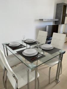 un tavolo in vetro con sedie e piatti bianchi di Dúplex Calero Sunset a Yaiza