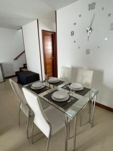 a dining room table with white chairs and a clock on the wall at Dúplex Calero Sunset in Yaiza