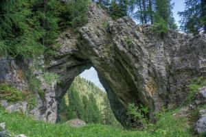 un arco in una montagna rocciosa con erba e alberi di Almhaus Goldeck a Schwaig