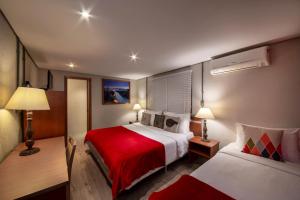 a hotel room with two beds and a red blanket at Hotel Britanico Express in Gramado
