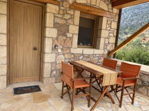 a wooden table and chairs in front of a stone house at Two-storey Mansion at the Sea in rkadiko Chorio
