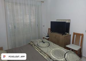 a bedroom with a bed and a flat screen tv at Comfort Apartment in Tirana
