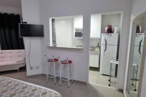 a kitchen with white cabinets and stools in a room at Reserva Ecológica do Sahy, Condado in Mangaratiba