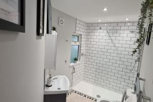 een witte badkamer met een wastafel en een bad bij Morris Lodge, Southampton - 1 bedroom, Free WIFI & Parking in Southampton