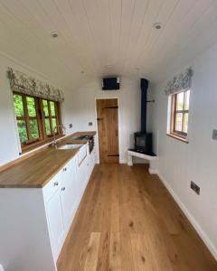 a kitchen with white cabinets and a wooden floor at The Snug at Coed Y Gaer in Oswestry