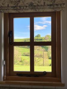 a window with a view of a green field at The Snug at Coed Y Gaer in Oswestry