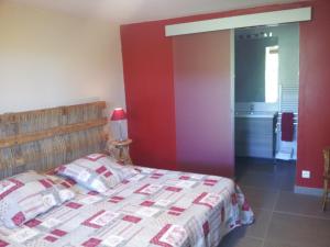 1 dormitorio con cama y pared roja en Chambres d'Hôtes Aux Tournesols, en Malaucène