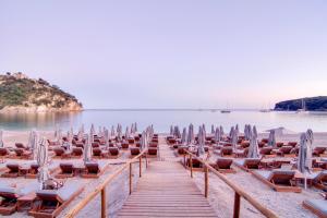 eine Reihe von Liegestühlen und Sonnenschirmen am Strand in der Unterkunft Valtos Beach Hotel in Parga