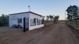 a small white building on the side of a dirt road at Cabañas Los Laureles Ruta del vino bc in Ensenada
