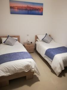 a bedroom with two beds and a painting on the wall at The Premier Suite - Fully Airconditioned - Ample Parking in Naxxar