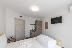una camera bianca con letto bianco e TV a schermo piatto di Мотел "Релакс" Motel "Relax", Балчик, a Balchik