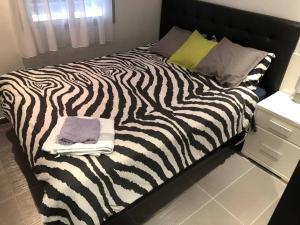 Una cama con estampado de cebra en un dormitorio con toallas. en Elche piso entero 3 dormitorios dobles en Elche