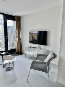 a white living room with a chair and a tv at NIEUW DOMBURG centrum - Luxe vakantiewoning 500 meter van strand met tuin en parkeerplaats & WIFI - Roosjesweg 2A in Domburg