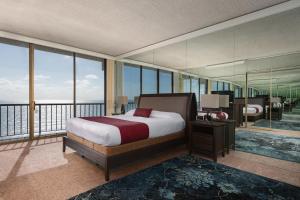 a bedroom with a bed and a balcony with windows at Capri by the Sea by All Seasons Resort Lodging in San Diego