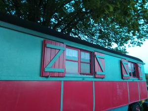 a red and blue train car with windows on it at La Roulotte De Lola - Chambre d'hôtes in La Celle