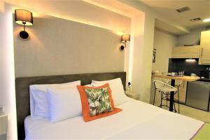 een slaapkamer met een wit bed met een oranje kussen erop bij Aiolos Apartments Ermou 64 2nd Floor suites in Athene