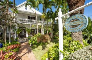 un cartel frente a una casa blanca con palmeras en The Mermaid & The Alligator en Key West