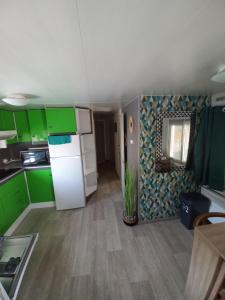 a kitchen with green cabinets and a white refrigerator at Mobilhome in Pornic