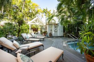 un patio con sofás y una piscina con palmeras. en The Mermaid & The Alligator en Cayo Hueso