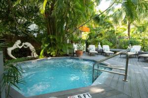 una piscina en un jardín con palmeras en The Mermaid & The Alligator en Cayo Hueso