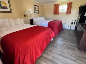 two beds in a hotel room with red sheets at Beachway Motel in Salisbury