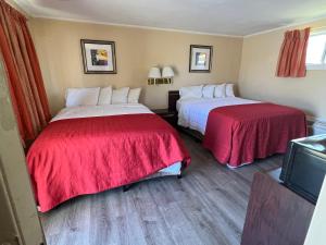 a hotel room with two beds with red sheets at Beachway Motel in Salisbury