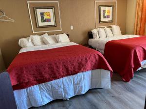 two beds in a hotel room with red and white sheets at Beachway Motel in Salisbury