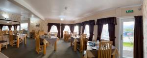 a dining room with tables and chairs and windows at White Heather Hotel in Kyleakin