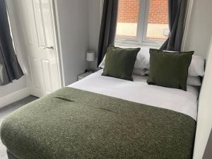 um quarto com uma cama com almofadas verdes e uma janela em Central Southsea Boutique 2 Bedroom Flat em Portsmouth