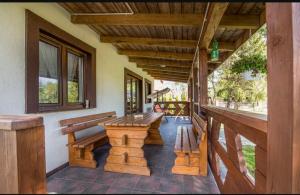 a porch with benches and a table and windows at Biały domek nad stawem in Huta Wielka