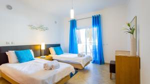 two beds in a room with blue curtains at Quinta da Arbrotea in Lagos +46 photos