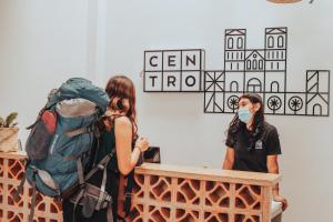 two women wearing face masks standing at a table with a backpack at Centro Hostel Medellin in Medellín