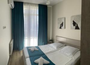 a bedroom with a bed with blue curtains and a window at Maia's Sweet Homes in Batumi