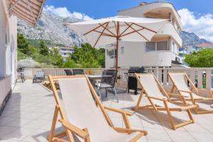 a group of chairs and an umbrella on a patio at House Santro in Baška Voda