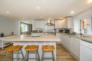a kitchen with white cabinets and a large island with stools at Penbarden Barn in Bude