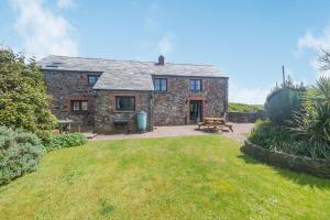 an old stone house with a picnic table in the yard at Penbarden Barn in Bude