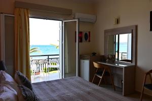 a bedroom with a bed and a desk and a balcony at Nadia's Studios & Apartments in Argasi, Sea-View in Argasi