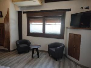 Habitación con 2 sillas, mesa y TV. en Hostal Suetxe, en Los Arcos