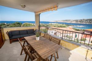 a balcony with a table and a couch and the ocean at Fronte Mare Capo Testa in Santa Teresa Gallura